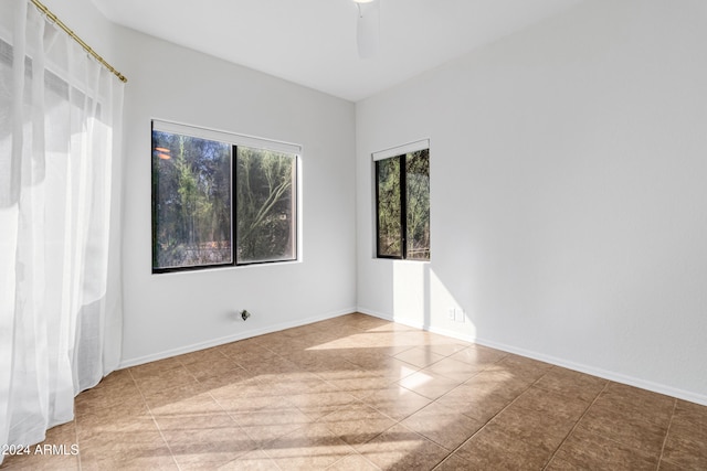 tiled empty room featuring ceiling fan