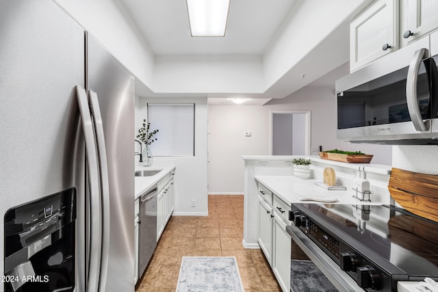 kitchen featuring appliances with stainless steel finishes, light tile patterned floors, white cabinetry, and sink