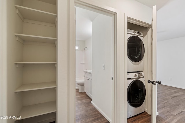 clothes washing area featuring wood-type flooring and stacked washing maching and dryer