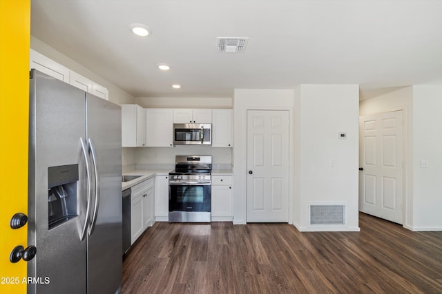 kitchen with dark wood-type flooring, white cabinets, and appliances with stainless steel finishes