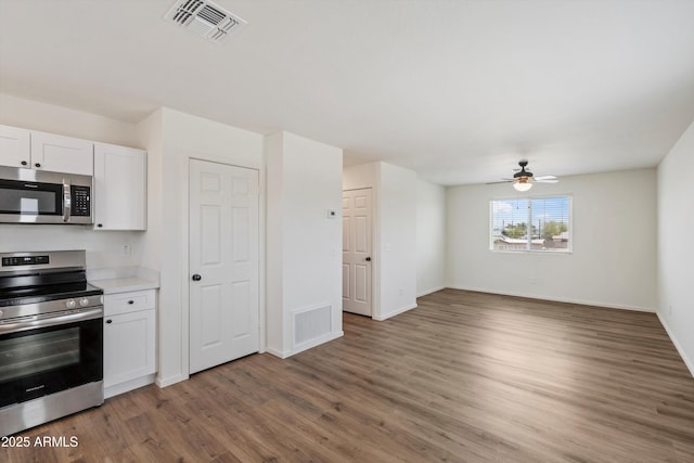 kitchen with ceiling fan, white cabinetry, appliances with stainless steel finishes, and dark hardwood / wood-style flooring