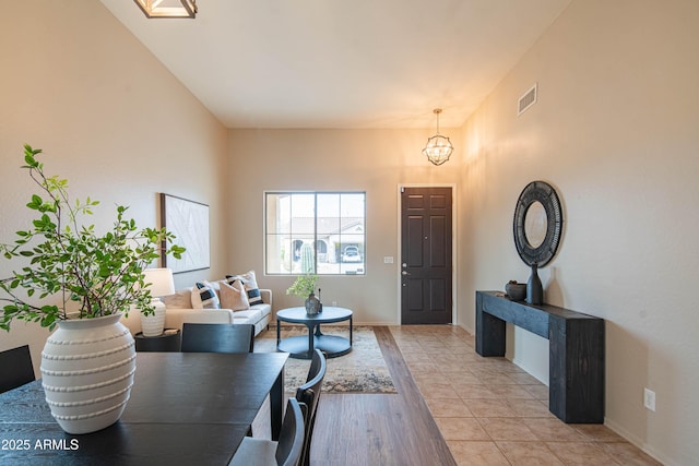 interior space with visible vents, light wood finished floors, baseboards, and an inviting chandelier