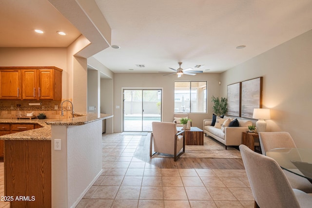 living area featuring light tile patterned floors, baseboards, and a ceiling fan