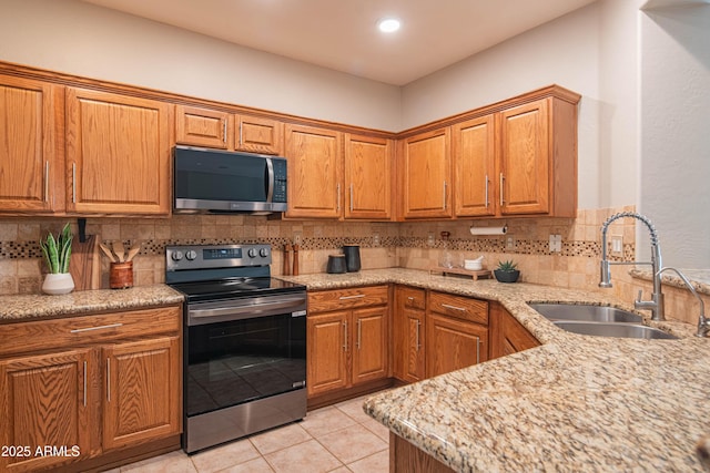 kitchen with stainless steel appliances, tasteful backsplash, brown cabinetry, and a sink