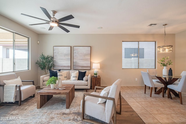 living area with light tile patterned floors, ceiling fan, and visible vents