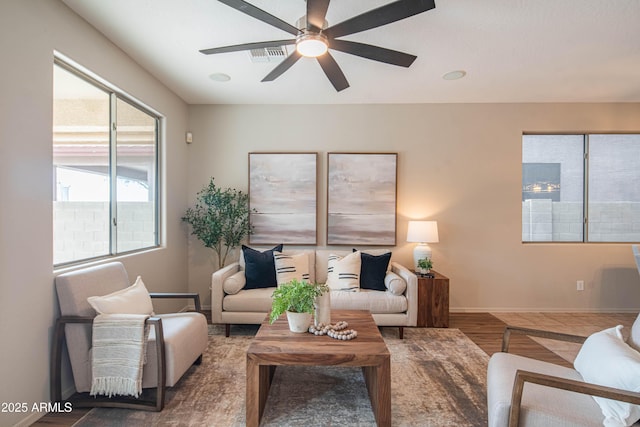 living area with a ceiling fan, visible vents, and baseboards