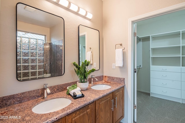 full bath with double vanity, a walk in closet, and a sink