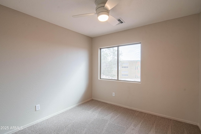 carpeted empty room featuring ceiling fan, visible vents, and baseboards