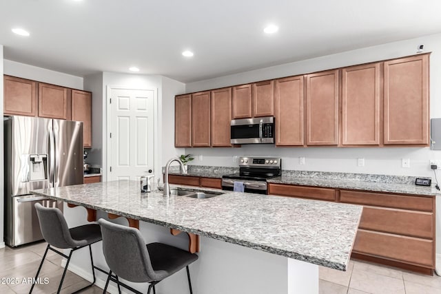 7910 S 33rd Ln, Laveen, AZ 85339 - kitchen with appliances with stainless steel finishes, light tile patterned floors, a kitchen breakfast bar, recessed lighting, and brown cabinetry