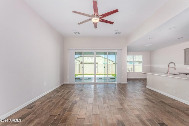 unfurnished living room featuring ceiling fan and sink