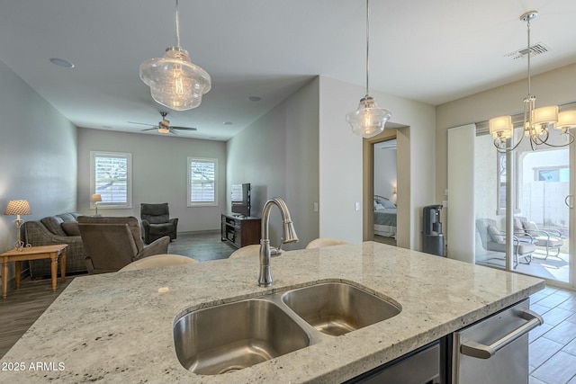 kitchen with light stone counters, wood-type flooring, decorative light fixtures, and sink