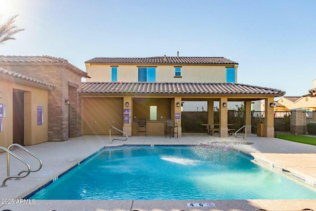 back of property featuring a community pool and a patio area