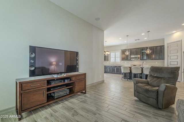 living room with an inviting chandelier, sink, and light hardwood / wood-style floors