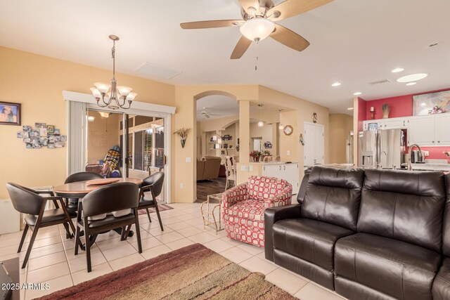 tiled living room with sink and ceiling fan with notable chandelier