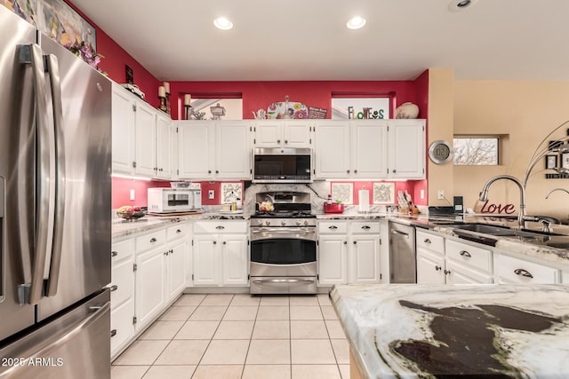 kitchen featuring sink, stainless steel appliances, white cabinets, and light stone countertops