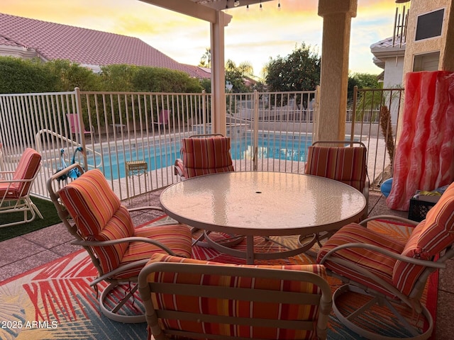 patio terrace at dusk featuring a fenced in pool