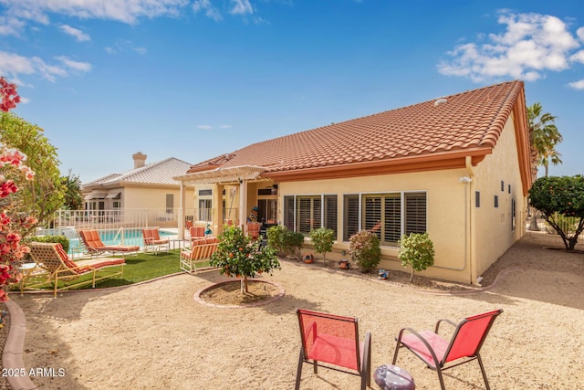 rear view of house featuring a fenced in pool, a pergola, and a patio