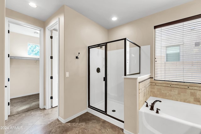 bathroom with a walk in closet, recessed lighting, a shower stall, baseboards, and a bath