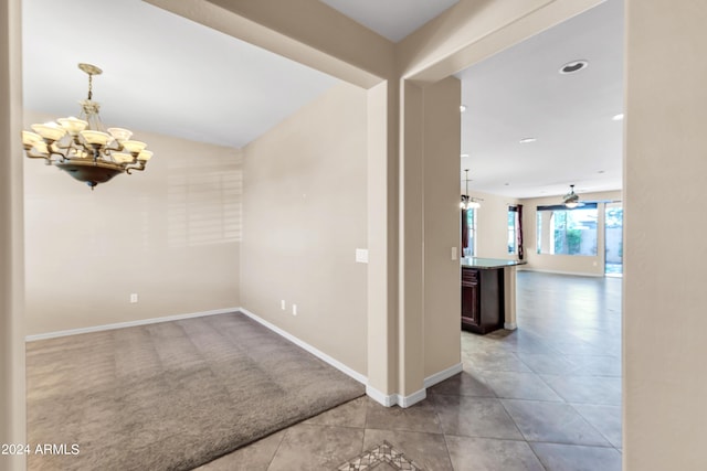 tiled empty room with an inviting chandelier, carpet, and baseboards