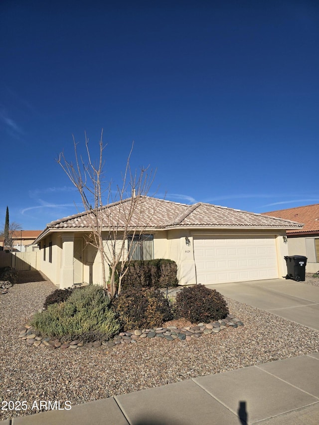 view of front facade with a tile roof, driveway, an attached garage, and stucco siding