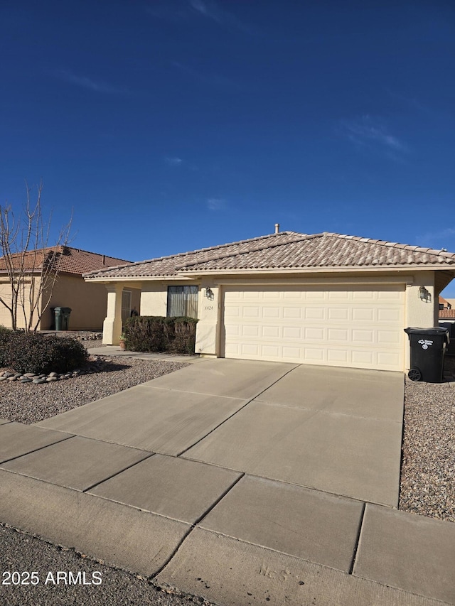 view of front of house featuring a garage, driveway, a tile roof, and stucco siding