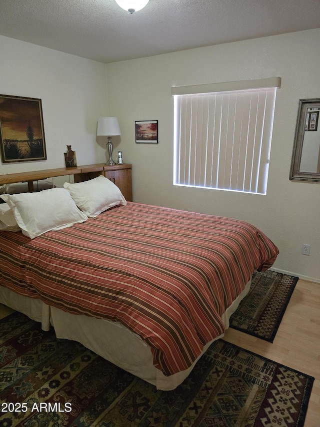 bedroom with a textured ceiling and wood finished floors