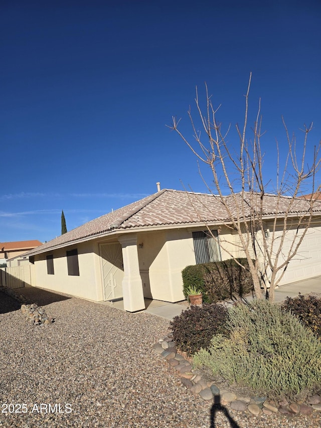 view of side of property featuring a tile roof, fence, and stucco siding