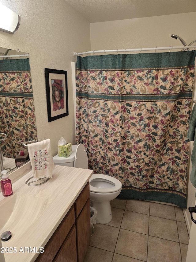bathroom with toilet, curtained shower, tile patterned flooring, a textured wall, and vanity