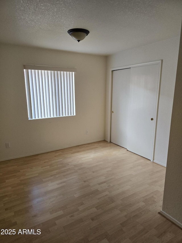unfurnished bedroom featuring wood finished floors, a textured ceiling, and a closet
