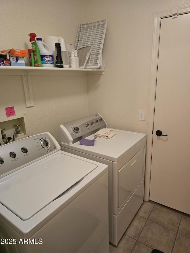 washroom with washing machine and clothes dryer, light tile patterned floors, and laundry area