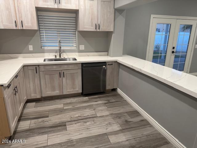 kitchen featuring light stone countertops, dishwasher, french doors, sink, and light hardwood / wood-style floors