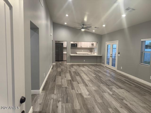 unfurnished living room featuring french doors, vaulted ceiling, ceiling fan, and wood-type flooring