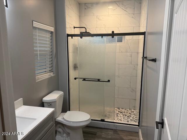 bathroom featuring vanity, wood-type flooring, an enclosed shower, and toilet