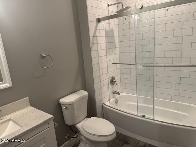 full bathroom with combined bath / shower with glass door, vanity, and toilet