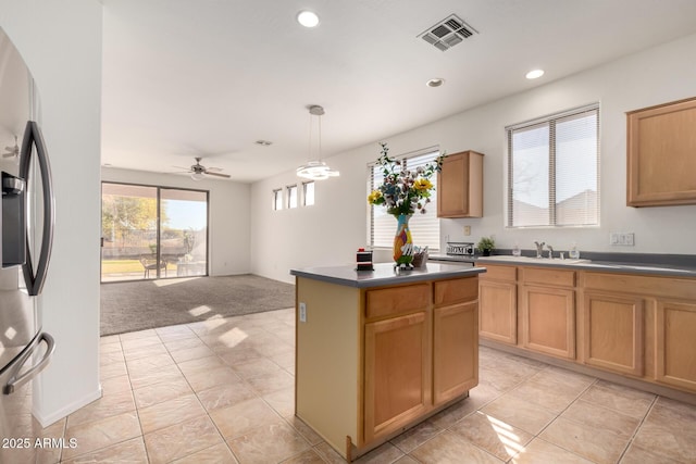 kitchen featuring decorative light fixtures, sink, stainless steel fridge, a center island, and ceiling fan