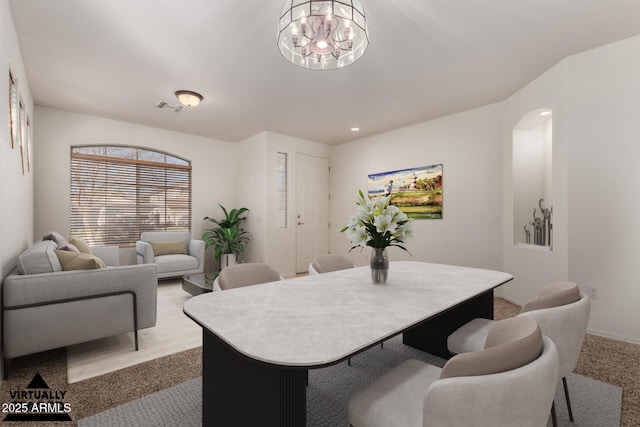 carpeted dining room with an inviting chandelier