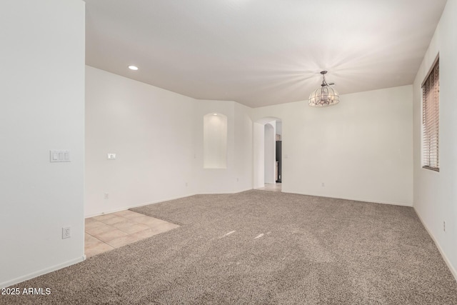 carpeted empty room with a notable chandelier