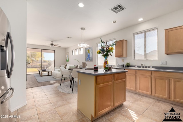 kitchen featuring sink, decorative light fixtures, a center island, stainless steel fridge, and ceiling fan