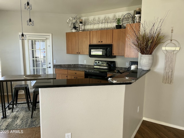 14250 W Wigwam Blvd Unit 812, Litchfield Park, AZ 85340 - kitchen featuring dark countertops, a peninsula, black appliances, dark wood-type flooring, and pendant lighting