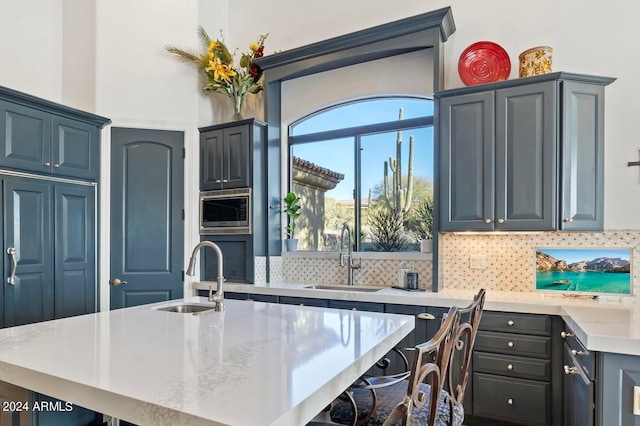 kitchen with a kitchen breakfast bar, a kitchen island with sink, sink, and tasteful backsplash