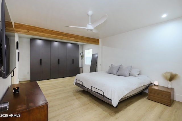 bedroom featuring beam ceiling, light hardwood / wood-style floors, and ceiling fan