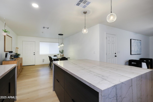 kitchen featuring pendant lighting, a kitchen island, and light hardwood / wood-style flooring