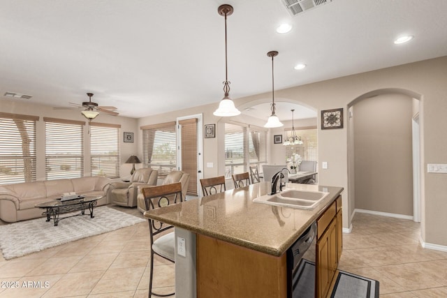 kitchen featuring dishwasher, a sink, arched walkways, and visible vents