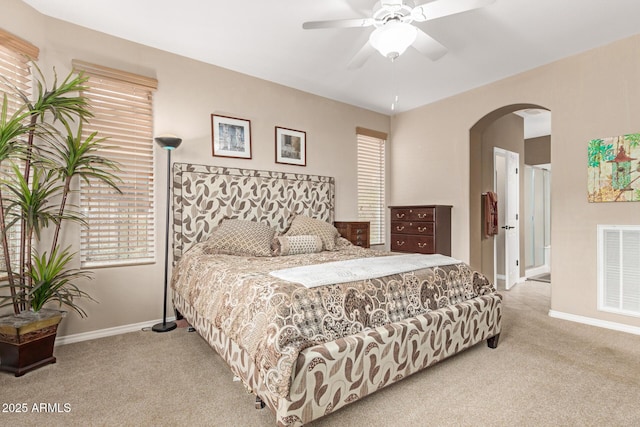 carpeted bedroom with arched walkways, ceiling fan, visible vents, and baseboards