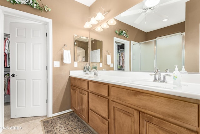 full bathroom featuring double vanity, tile patterned floors, a spacious closet, a shower stall, and a sink