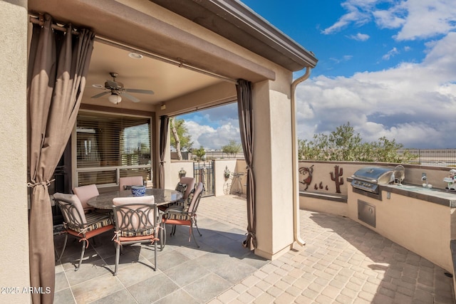 view of patio / terrace featuring an outdoor kitchen, a ceiling fan, a grill, fence, and outdoor dining space