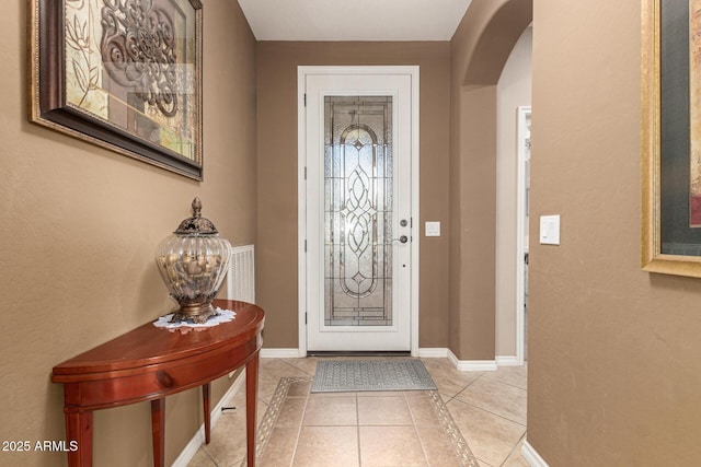 entryway featuring baseboards, arched walkways, and light tile patterned flooring