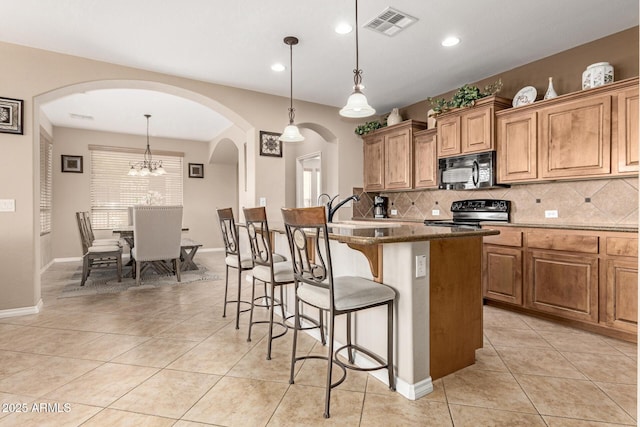 kitchen with black microwave, a sink, visible vents, a kitchen breakfast bar, and electric stove