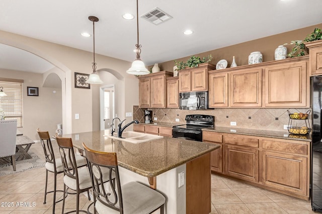 kitchen featuring arched walkways, visible vents, light tile patterned flooring, a sink, and black appliances