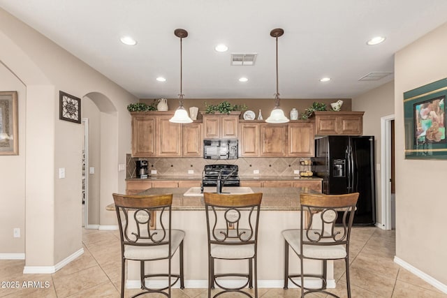 kitchen featuring black appliances, a sink, visible vents, and a kitchen breakfast bar